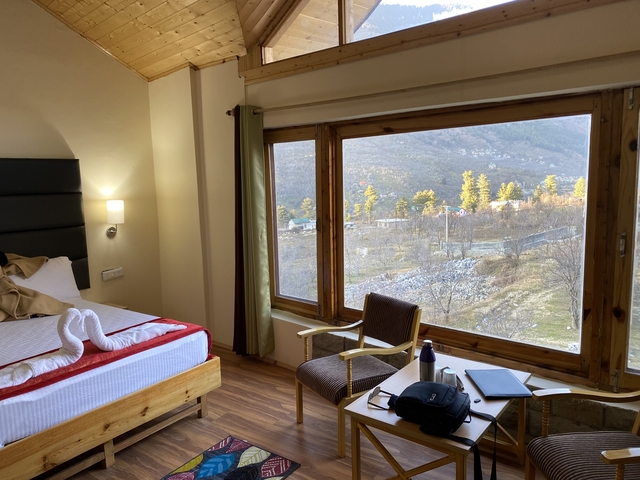 A hotel room with a large window showing a serene landscape view.
