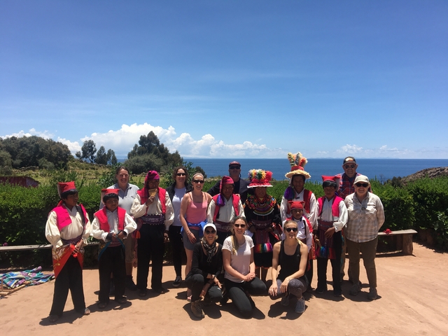       Group with locals in vibrant attire by a lake.
  