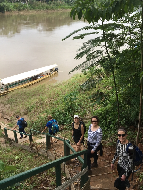       People walking in nature down towards a river.
  