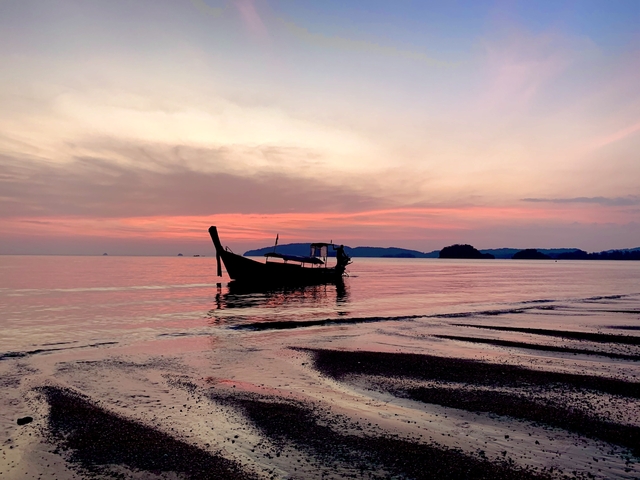 A serene sunset view of a traditional wooden boat on the water.