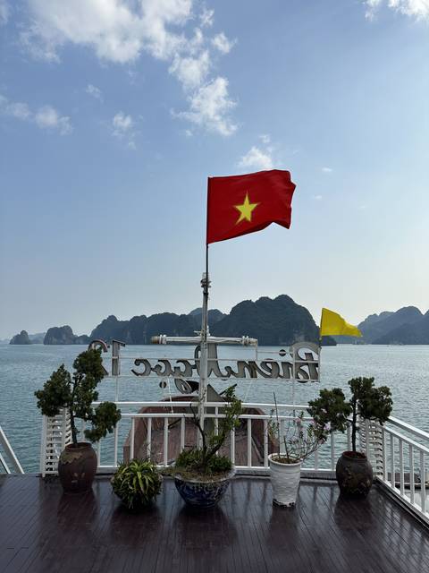       A red Vietnamese flag on a boat with a scenic water background in Halong Bay.
  