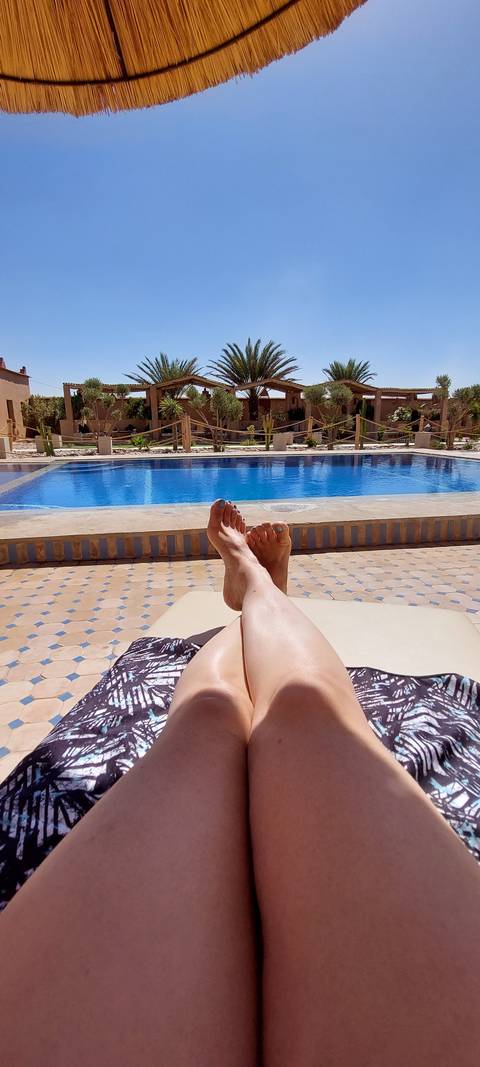       A person relaxing by the pool with feet in the foreground.
  