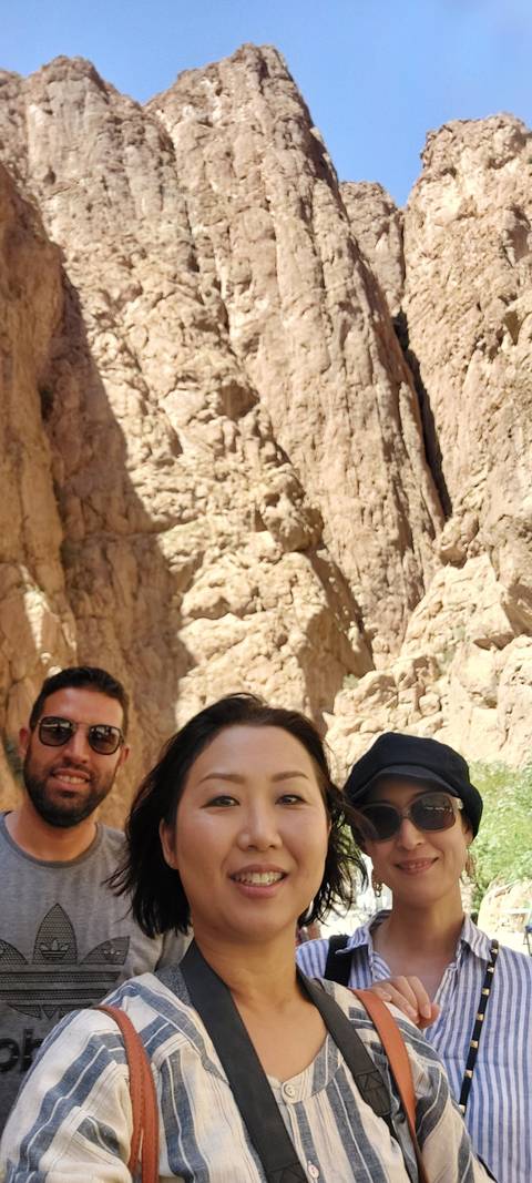       Three people posing in a rocky desert landscape.
  