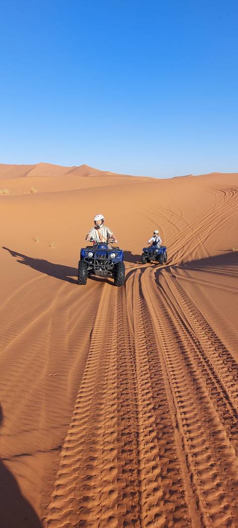       ATV riders on red desert dunes.
  