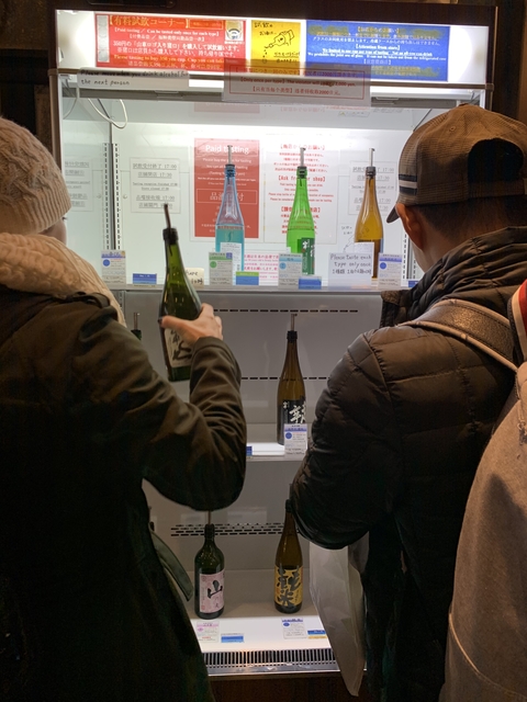 People tasting different bottles of sake.