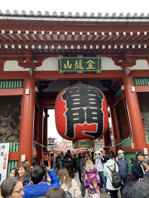 A close-up of a large red lantern at a temple gate.