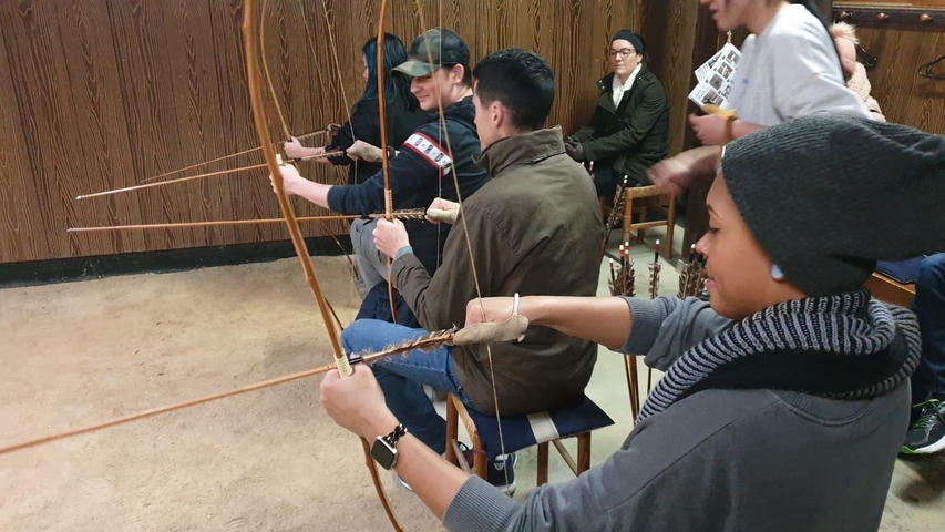 People practicing archery indoors.