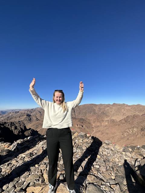 Person standing on rocky terrain with arms raised.