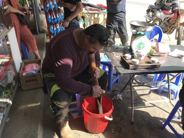 A person preparing a wooden press in an outdoor market area.