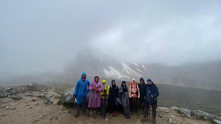       Hikers in a foggy mountain area dressed in colorful rain gear.
  