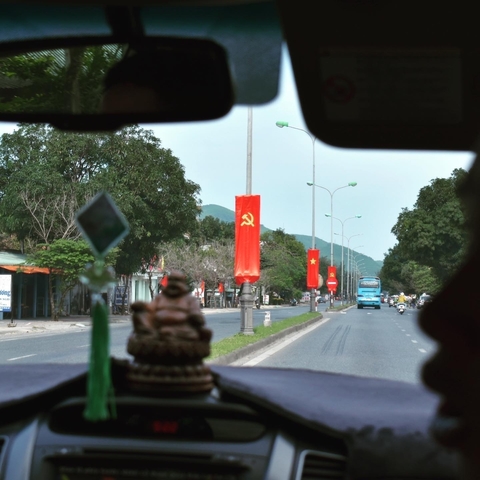       View from inside a vehicle showing a road lined with flags.
  