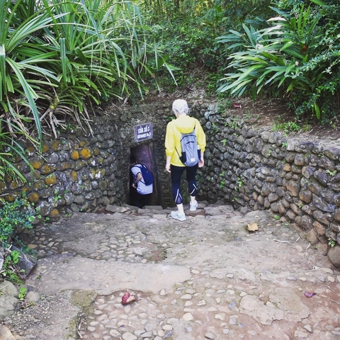       Tourists entering a tunnel in a historic site.
  