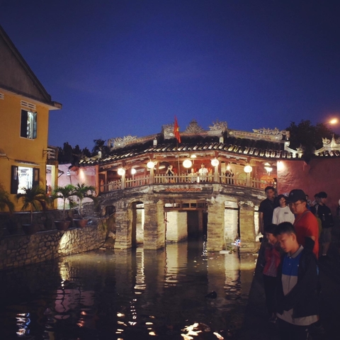       Japanese bridge at night with people standing around.
  