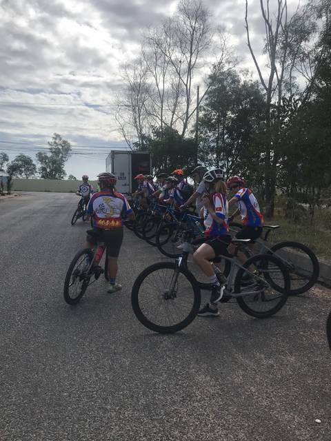 Cyclists lining up on a road in colorful gear.