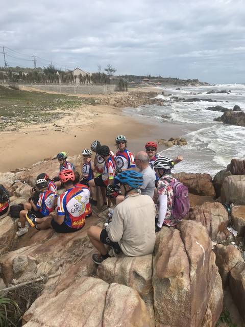 Cyclists resting by the beach on rocks.