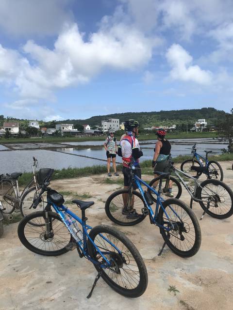 Cyclists with bikes by a water body.