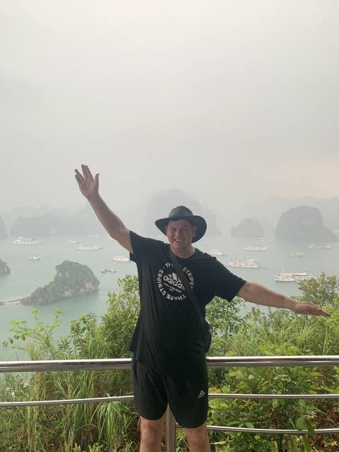 Person posing with arms outstretched overlooking water and islands