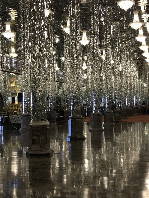 Hall with ornate mirrored columns and decorations.