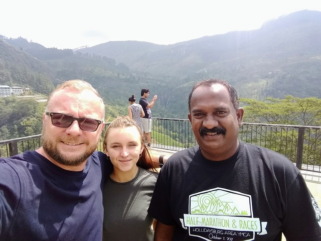 Three people posing with a mountainous backdrop.