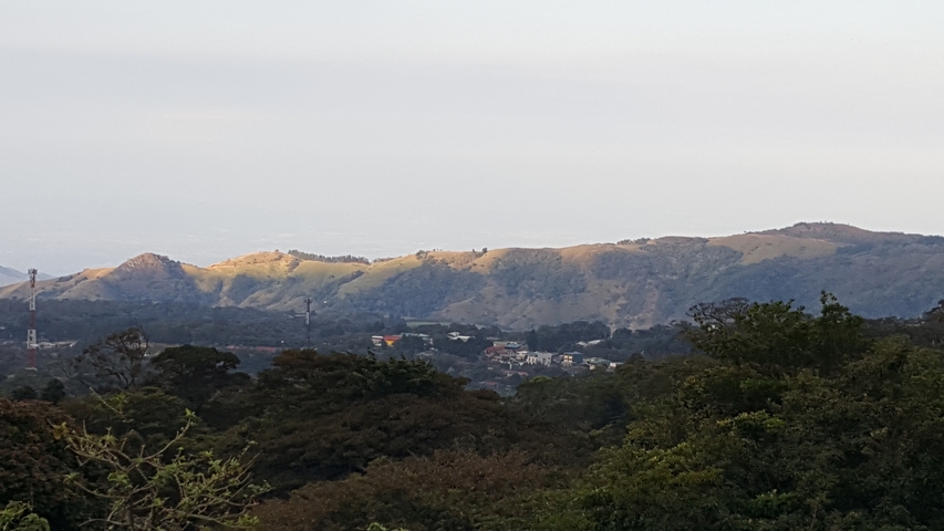 Distant view of hills with scattered trees and small settlements.