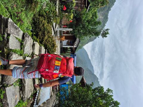       Hiker with backpack on stone path, with mountainous background.
  