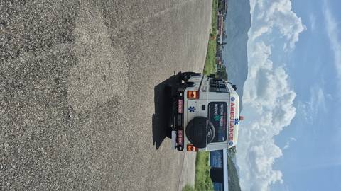       Ambulance parked on roadside with mountains in the background.
  