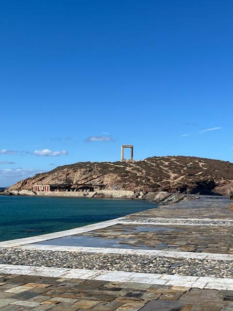 A large stone arch next to the ocean.