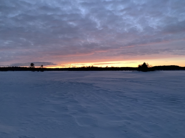 Snow-covered landscape during sunset.
