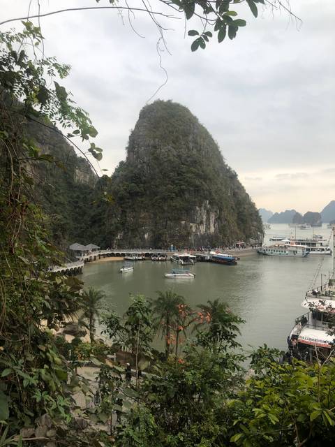       View of limestone karsts and boats in a bay.
  