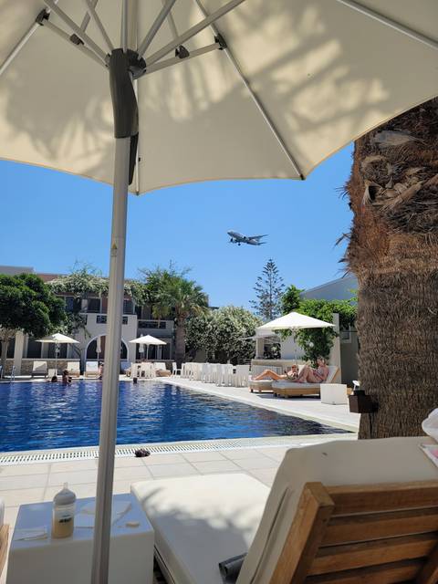       Outdoor pool area with beach chairs and plane overhead.
  