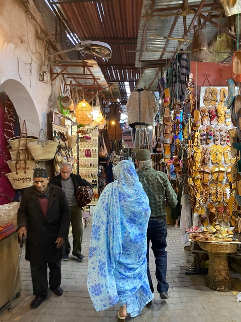       Busy market street with people shopping and colorful goods on display.
  