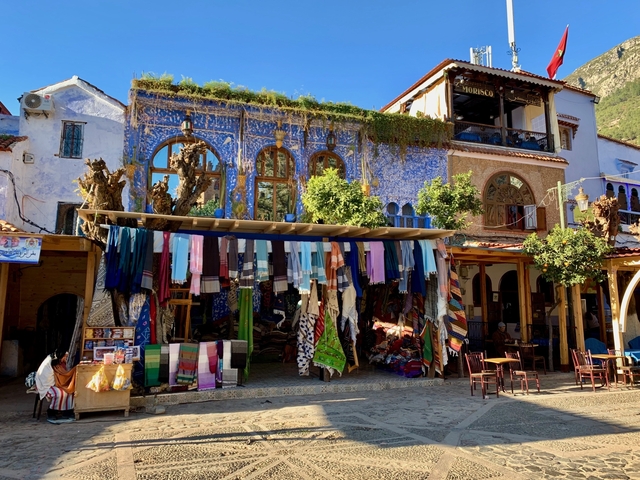      Colorful shop facades selling textiles in a vibrant market.
  