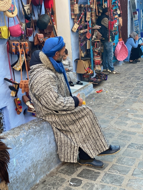       Man sitting with a drink in a traditional market alley.
  