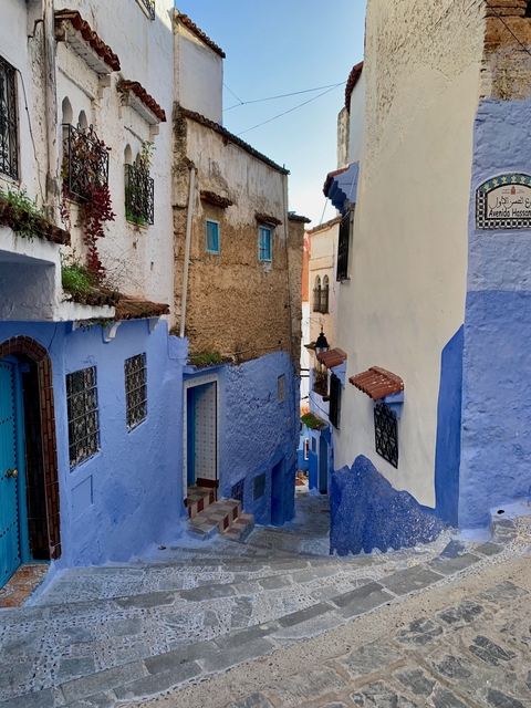       Narrow blue-painted street in a historic town.
  