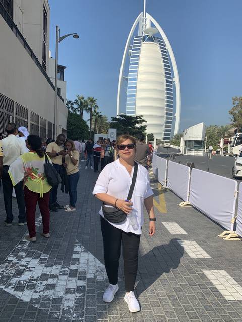Person standing on a pathway with a landmark in the background.