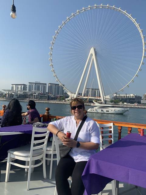 Person sitting in an outdoor dining area with a Ferris wheel in the background.