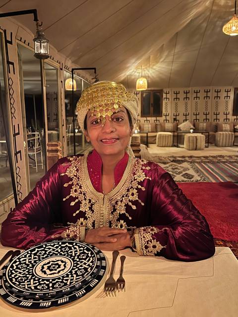       Person wearing traditional attire at a table.
  