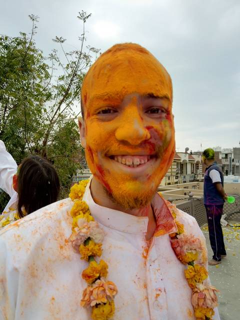       Man with face covered in orange color powder.
  