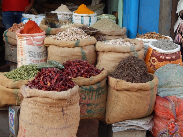 Market stall displaying varieties of spices in sacks.