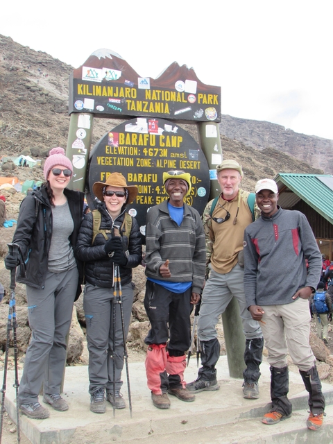 Group of people posing with hiking gear at mountain camp.