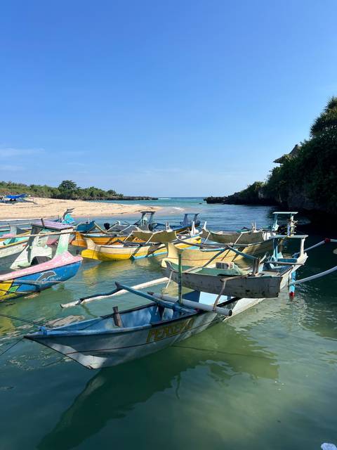 Boats docked at a lakeside under a clear blue sky.