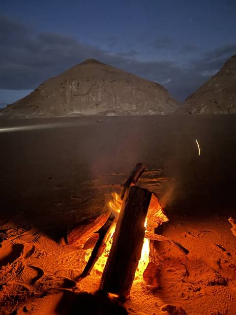 Campfire in a desert setting during twilight.