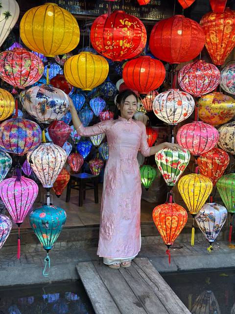 A person in traditional attire surrounded by colorful lanterns.