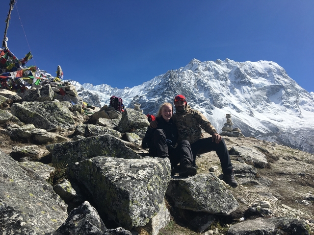 Two people sitting on rocks in a snowy mountain setting.