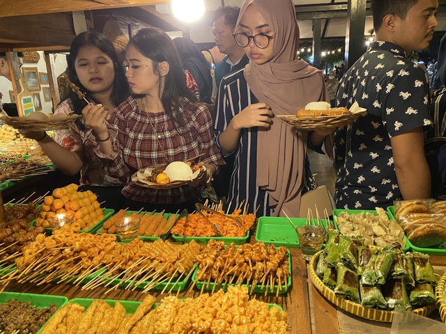       People enjoying street food at a bustling market.
  