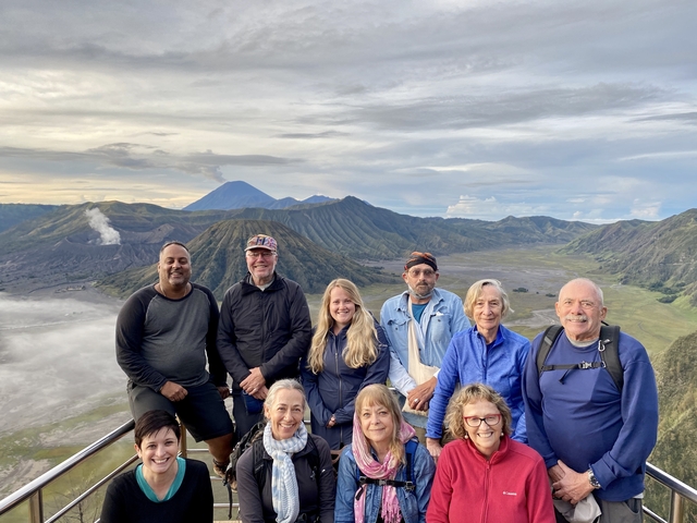      Group of people posing with a panoramic view of volcanic mountains.
  