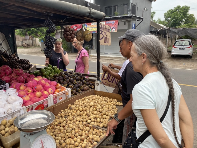       Tourists examining fruits at a roadside market.
  