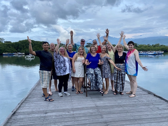      Group of people celebrating on a dock with mountains in the background.
  
