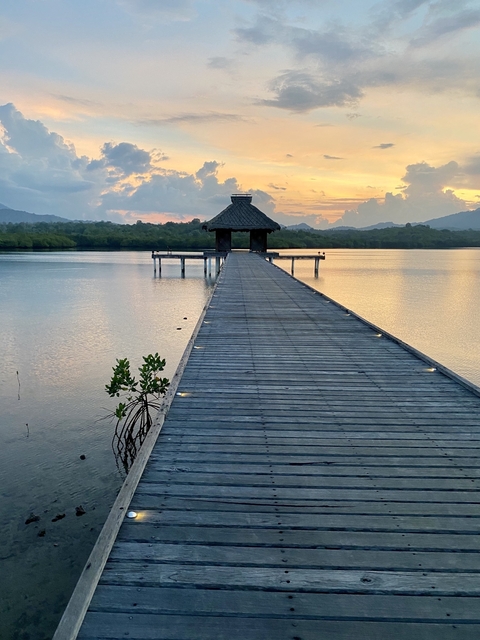       View of a pier at sunset over a calm lake.
  