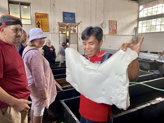       Person holding up a processed sheet in a factory setting.
  